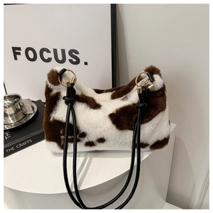 Detail of plush cow print shoulder bag with woven strap and gold metal hardware rings