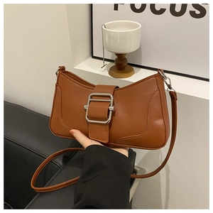 Détail d'un sac baguette marron avec une grande boucle argentée et cuir synthétique mat