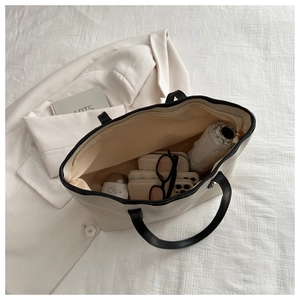 Interior view of large white canvas tote bag showing spacious storage with black straps