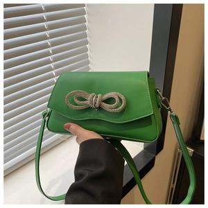Detail of green faux leather crossbody bag with sparkling rhinestone bow embellishment