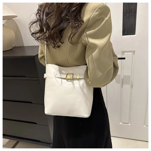 Detail of cream white bucket bag showing soft leather texture and golden metal hardware