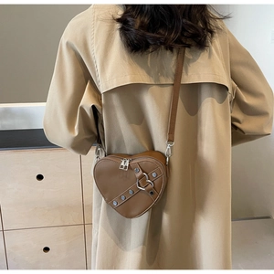 Detail of brown heart-shaped crossbody bag with metal rivets and double zipper design