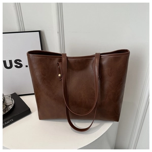 Vintage brown PU leather tote bag with long dual straps and rivet detail on a white pedestal