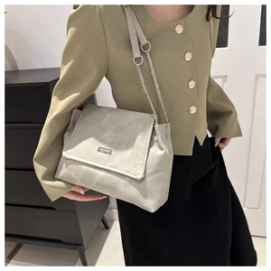 Detail of light grey matte crossbody bag with silver chain strap on model
