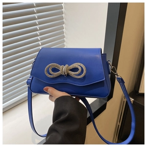 Detailed close-up of the rhinestone bow buckle on the Klein Blue leather crossbody bag