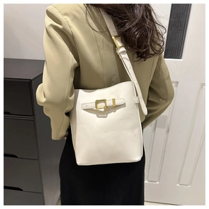 Detail of adjustable leather strap and gold buckle on white PU barrel shoulder bag