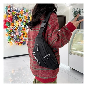 Gros plan d'un sac bandoulière en nylon noir montrant la sangle réglable et la boucle sur modèle