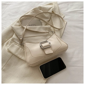 Détail du sac baguette en cuir crème minimaliste avec boucle argentée sur tissu
