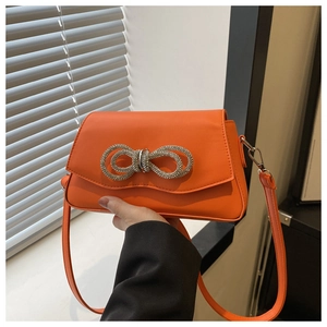 Detail of orange leather crossbody bag with sparkling silver rhinestone bow ornament