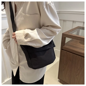 Detail of minimalist black crossbody bag with adjustable strap and durable fabric texture