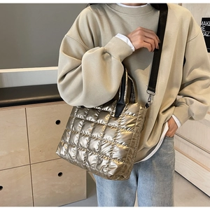 Gros plan du sac seau matelassé doré champagne avec bandoulière noire sur un mannequin