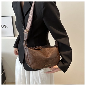 Detail of brown PU leather hobo bag with vintage texture and wide patterned strap