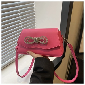 Detailed view of magenta crossbody bag featuring a large sparkling rhinestone bow accent