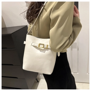 White leather bucket bag with gold buckle styled with a green blazer and indoor background