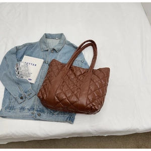 Close-up of brown quilted nylon tote bag with puffer texture on a lifestyle background