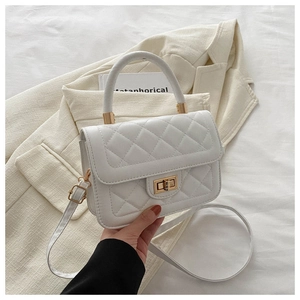 Détail d'un sac en similicuir matelassé blanc avec fermoir doré et poignée supérieure