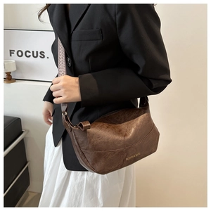 Detail of vintage brown hobo bag with textured leather and geometric woven strap
