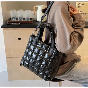 Détail d'un sac à bandoulière matelassé noir brillant avec sangle sur une mannequin