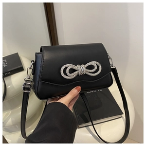 Detail of elegant black leather crossbody bag with a sparkling rhinestone bow decoration