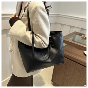 Detail shot of black faux leather tote bag with fine grain texture and slender straps