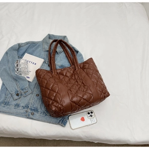 Detailed overhead shot of brown quilted tote bag with diamond texture on soft fabric
