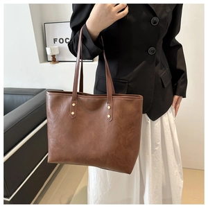 Detail of vintage brown PU leather tote bag with elegant cloud texture and gold rivets