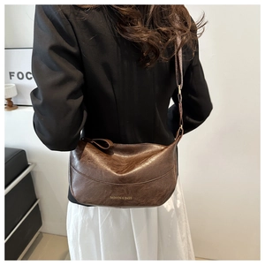 Detail showing the brown wrinkled PU leather texture and gold Fashion logo on the bag