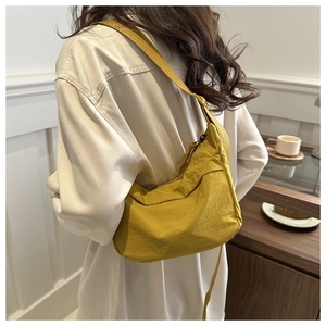 Detail of yellow crescent nylon crossbody bag with natural texture and black zipper