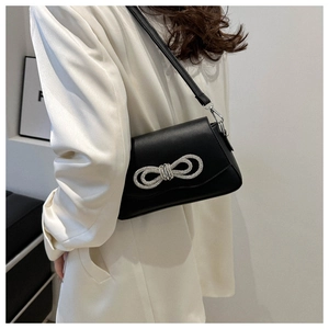 Detail of black leather crossbody bag with a large sparkling rhinestone bow on the flap