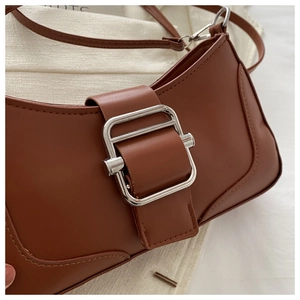 Détail du sac baguette en similicuir marron avec une grande boucle en métal argenté