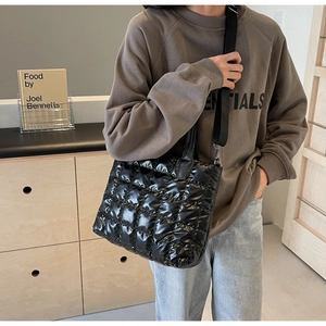 Détail du sac cabas matelassé noir avec large bandoulière et texture tissu brillant