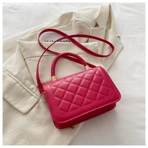 Détail du sac bandoulière matelassé rose rouge avec finitions dorées sur blazer
