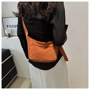 Detailed back view of an orange nylon crossbody bag with a wide adjustable shoulder strap