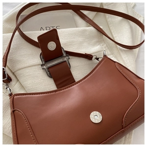 Gros plan du sac baguette marron avec boucle magnétique et texture en cuir lisse