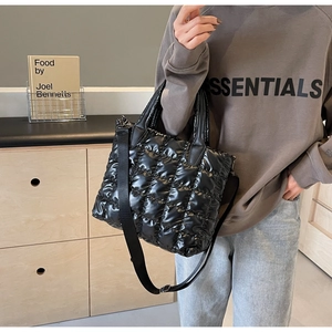 Gros plan du sac fourre-tout noir matelassé brillant avec bandoulière et doubles poignées