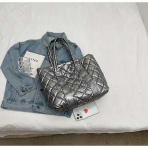 Close-up of quilted silver puffer tote bag showing metallic nylon texture and stitching