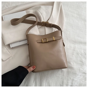 Detail view of brown leather bucket bag with gold buckle and adjustable shoulder strap