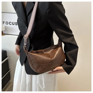 Detail of vintage brown pu leather dumpling bag with wide geometric strap and gold hardware