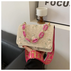 Détail du sac bandoulière en paille avec broderie florale rose et sangle tissée