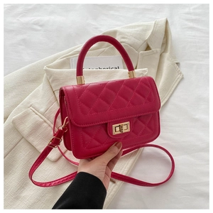 Gros plan d'un sac matelassé fuchsia avec fermoir doré sur un tissu en tweed
