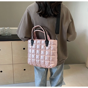 Detail of pink quilted tote bag showing waterproof fabric and wide black shoulder strap