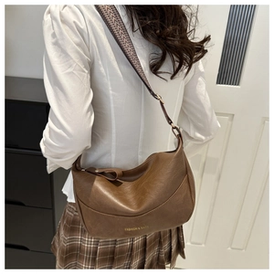 Close-up of brown PU leather moon bag featuring a colorful bohemian woven strap