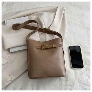 Detail of minimalist khaki bucket bag with metallic buckle and leather texture
