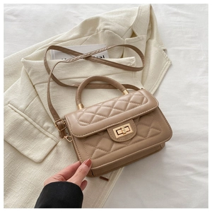 Détail d'un sac à main beige matelassé avec fermoir doré posé sur un blazer élégant