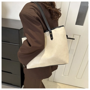 Lifestyle view of a large contrast tote bag in cream and black on a brown blazer