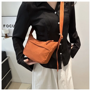 Detail of orange nylon crossbody bag with pleated texture and wide shoulder strap