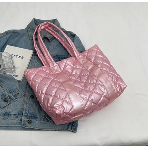 Detail of pink quilted puffer tote bag with glossy nylon finish on white fabric background