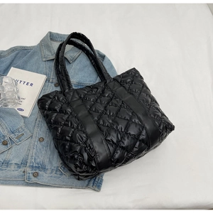 Chic black quilted puffer tote bag with glossy finish on a casual lifestyle background