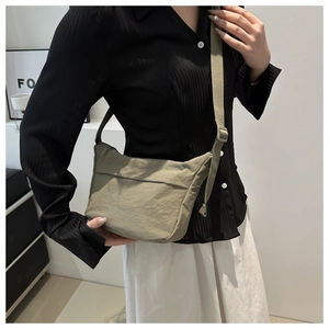Close-up of army green crossbody bag with pleated texture and wide adjustable strap