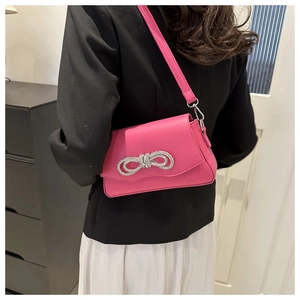 Close-up of bright pink leather crossbody bag with sparkling rhinestone bow detail